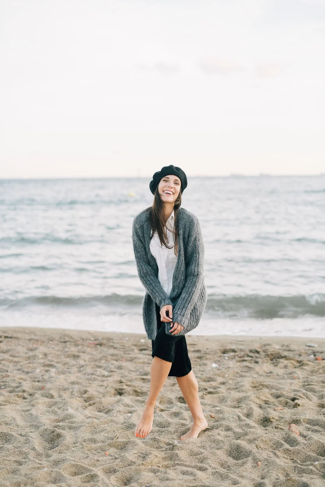 Grey/slate long open cardigan shown with a light blouse and dark skirt on a shore.
