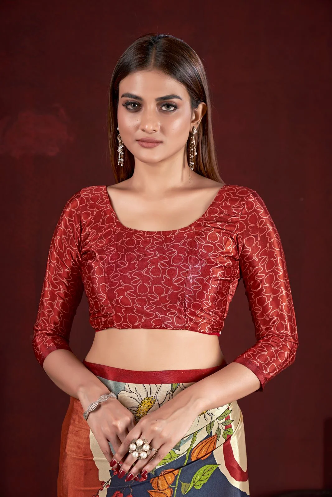 Warm red printed sari blouse with three-quarter sleeves, shown with a multicoloured sari.