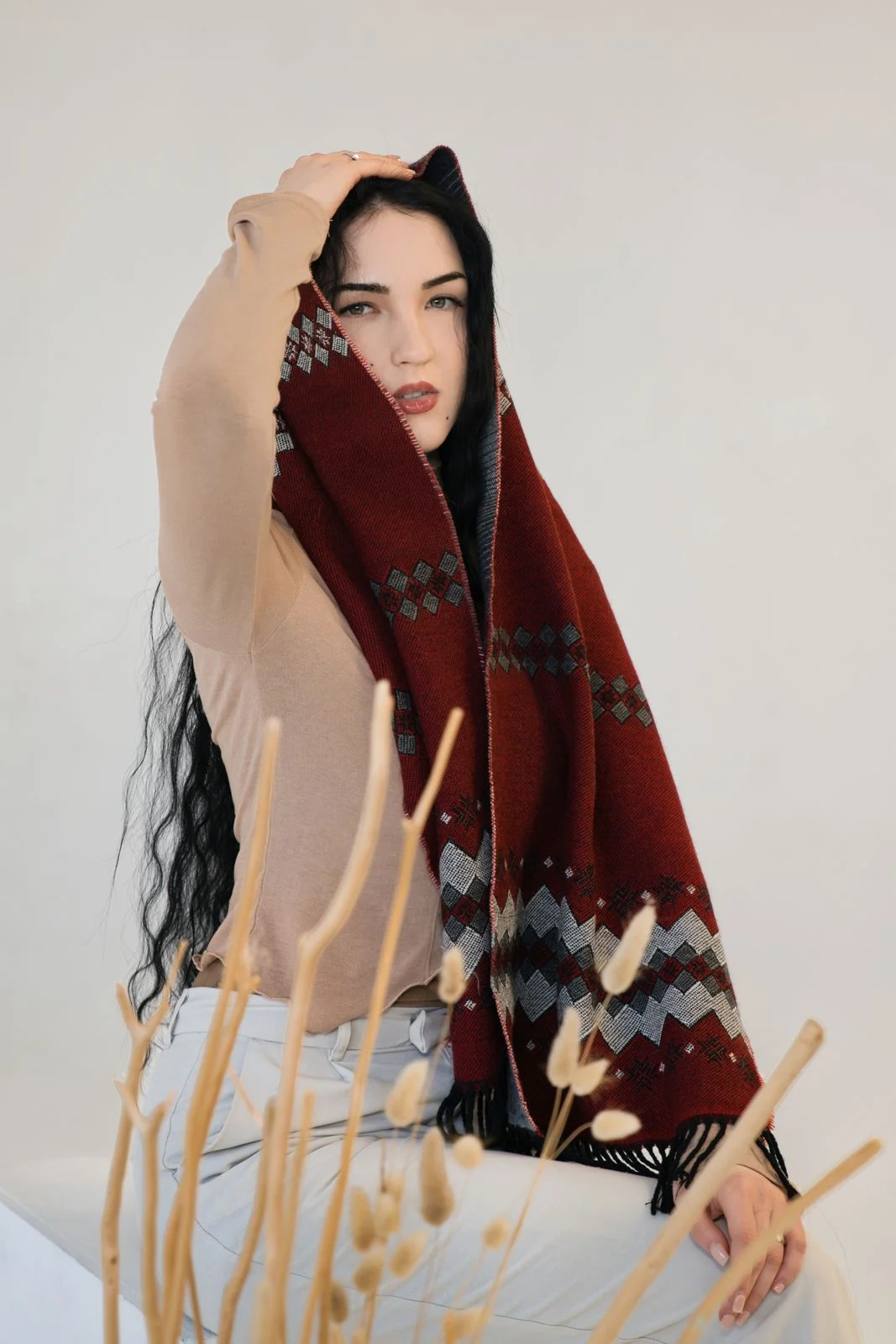 Red and charcoal geometric patterned shawl with fringed ends, draped view.