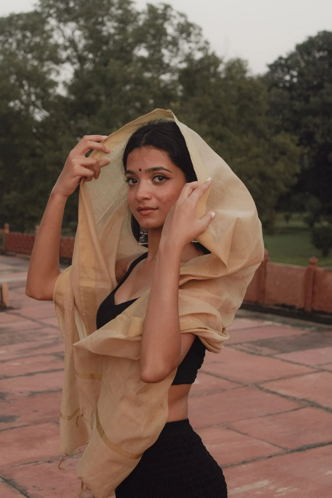 Light tan/gold-tone drape shown over the head and shoulder.