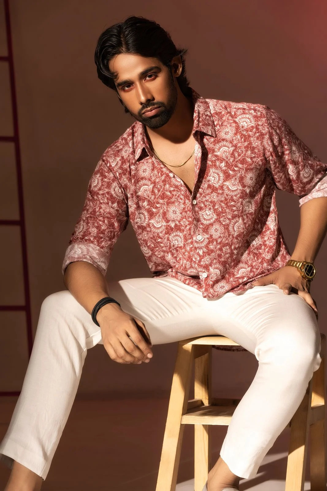 Warm red and pink floral shirt with a pointed collar, photographed with white trousers.