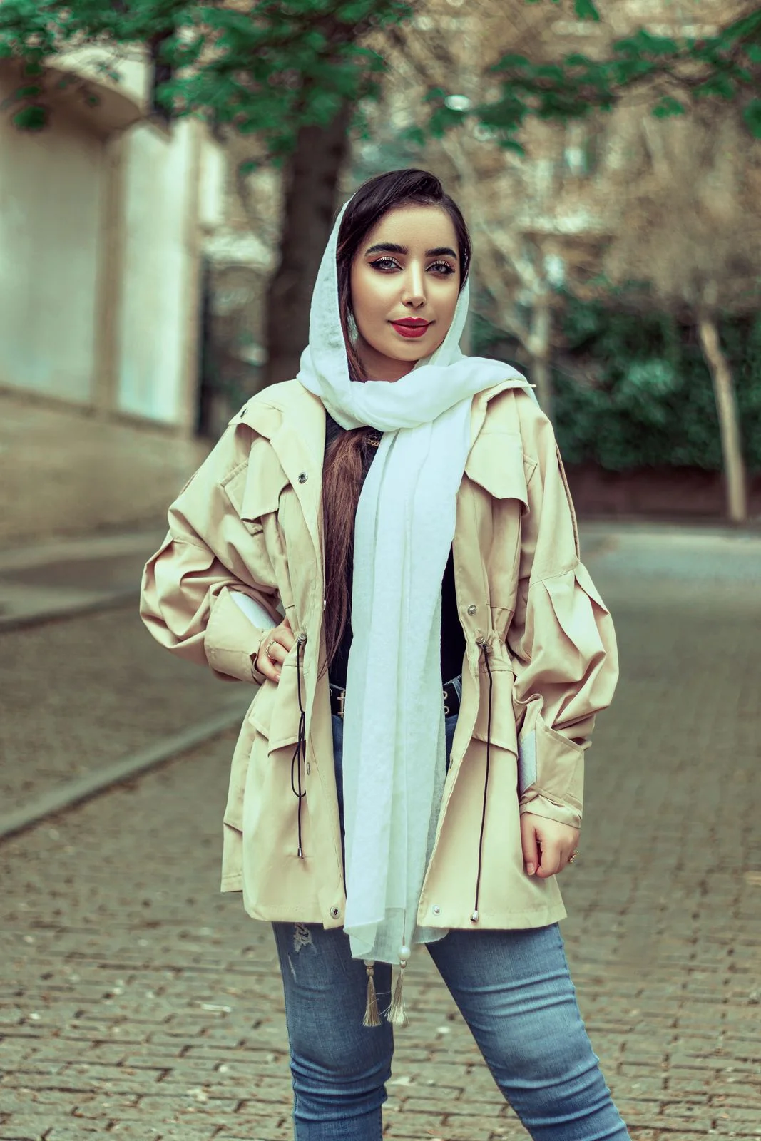 Light cream scarf with tasselled ends, photographed over a beige coat.